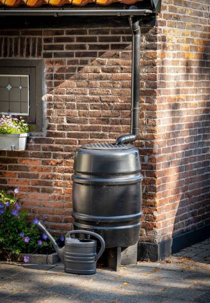 Black rain barrel against brick home