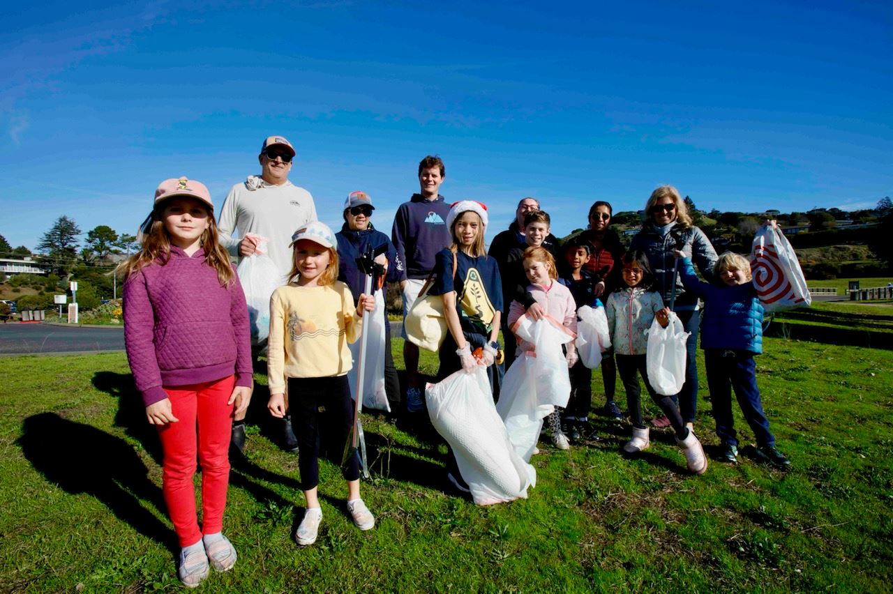 Group of Grateful Planet volunteers standing outside with trash bags and trash pickers