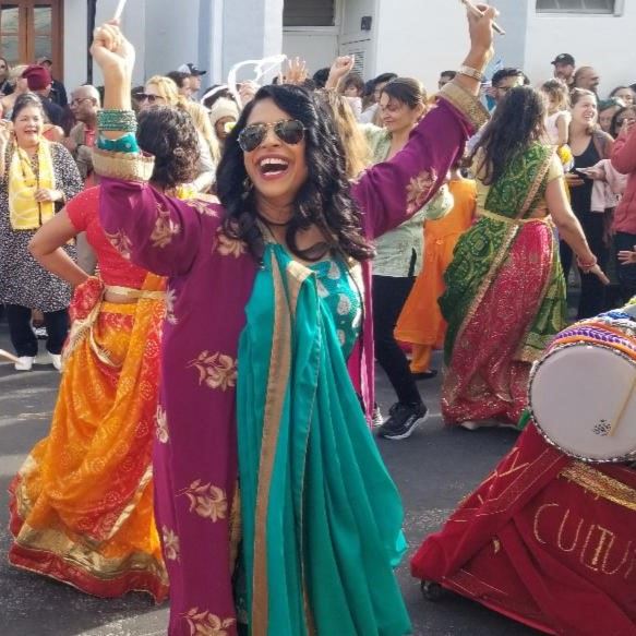 Woman in traditional Indian clothing dancing and smiling on Main Street in Tiburon