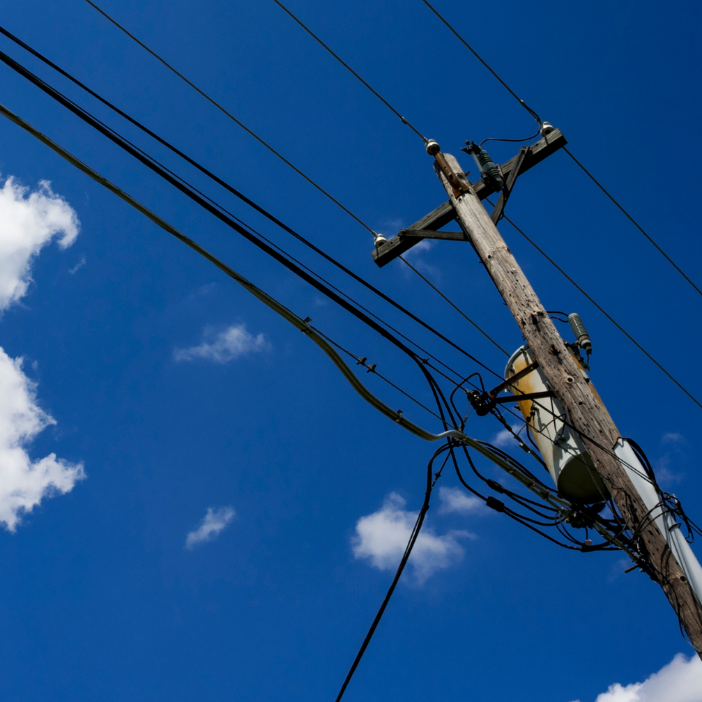 Telephone pole against a blue sky with clouds